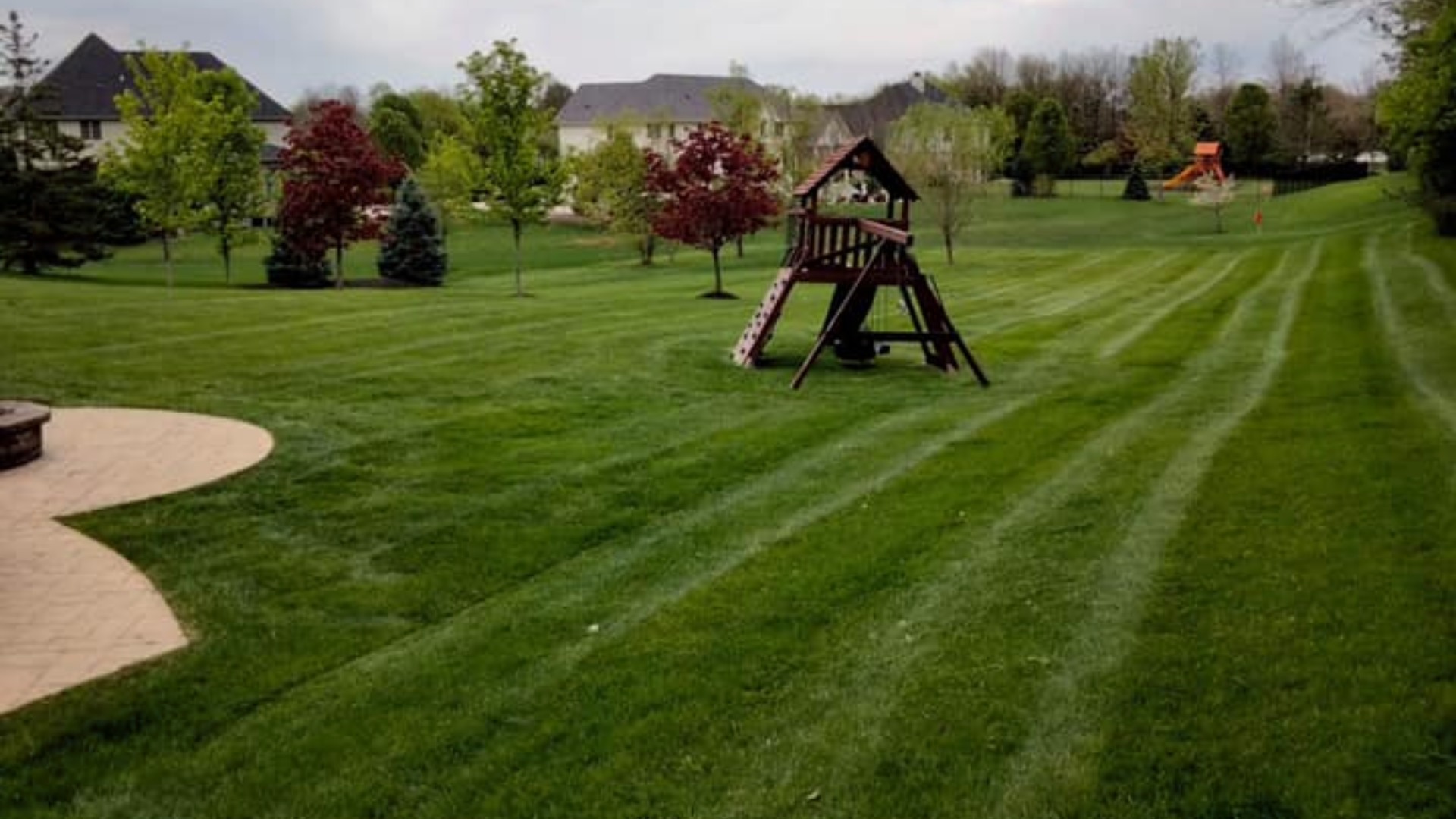 Backyard mowed with playground set in Noblesville, IN.
